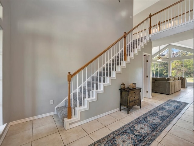 staircase with a towering ceiling and tile patterned floors