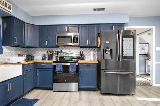 kitchen with blue cabinetry, butcher block counters, visible vents, and stainless steel appliances