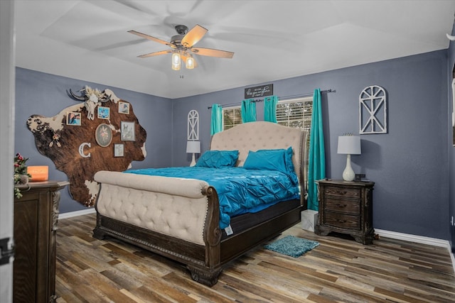 bedroom featuring hardwood / wood-style flooring, ceiling fan, and a raised ceiling