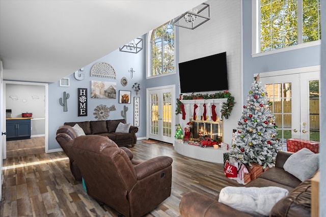 living room with a wealth of natural light, french doors, a towering ceiling, and dark hardwood / wood-style floors