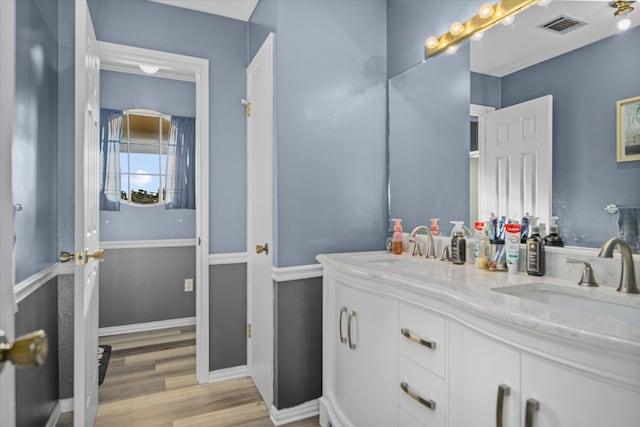 full bathroom with double vanity, baseboards, visible vents, wood finished floors, and a sink