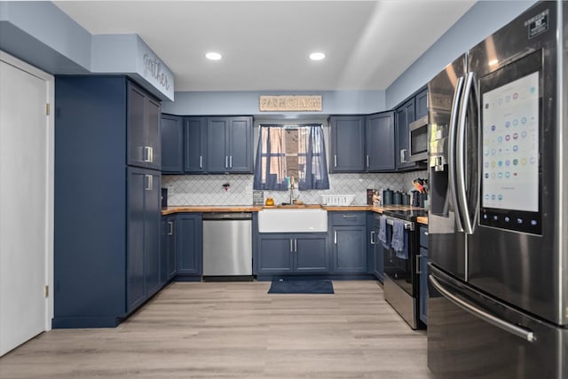 kitchen featuring stainless steel appliances, light wood-style floors, a sink, and backsplash