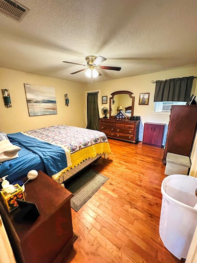 bedroom featuring ceiling fan, light hardwood / wood-style floors, and a textured ceiling