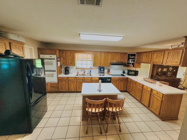 kitchen with black appliances, a kitchen island, and light tile patterned floors