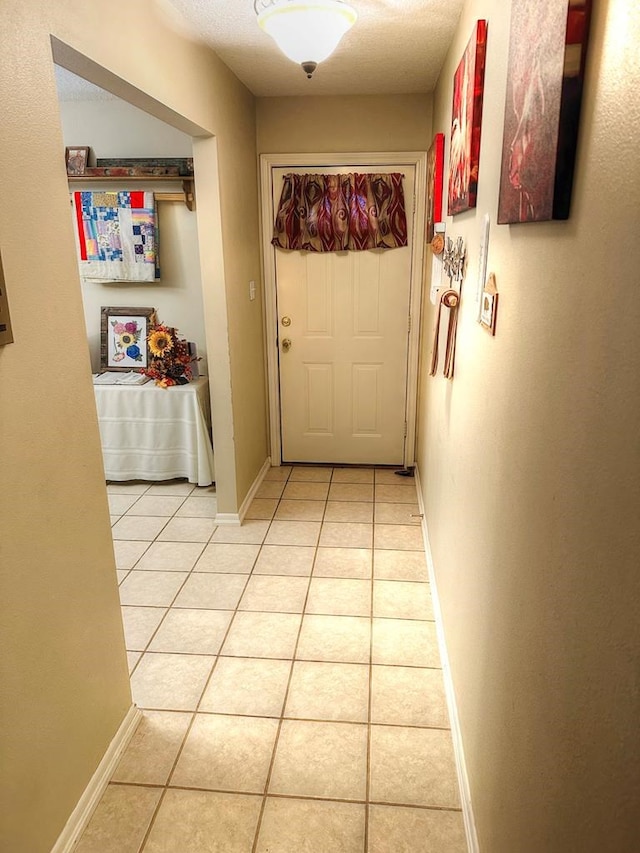 hallway featuring light tile patterned floors and a textured ceiling