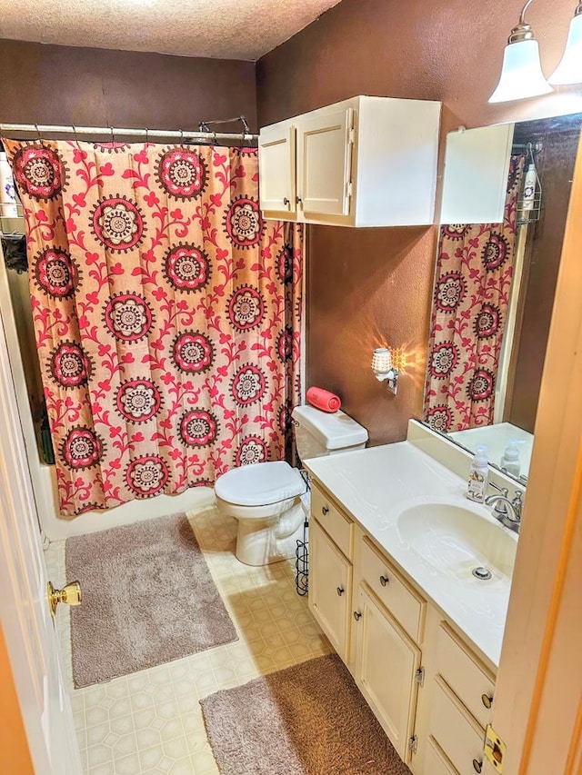 bathroom featuring a textured ceiling, vanity, toilet, and walk in shower