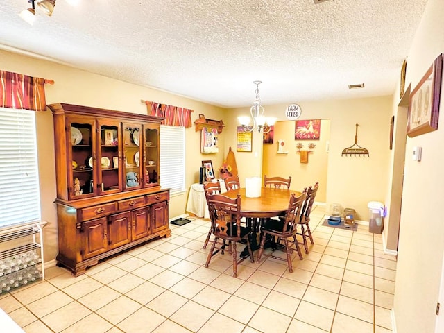 tiled dining room with a notable chandelier and a textured ceiling