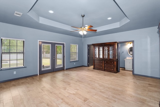 unfurnished bedroom with french doors, connected bathroom, a raised ceiling, and ceiling fan