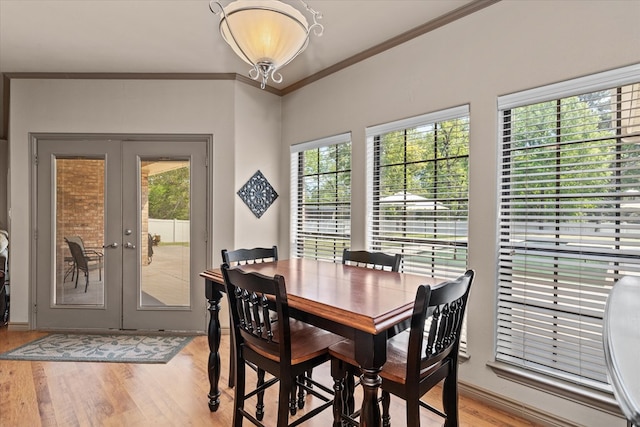 dining space featuring a wealth of natural light, french doors, crown molding, and light hardwood / wood-style flooring