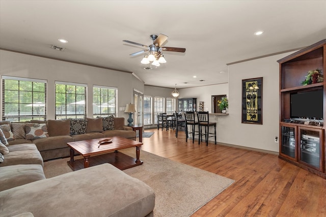 living room featuring light wood-type flooring, ceiling fan, and crown molding