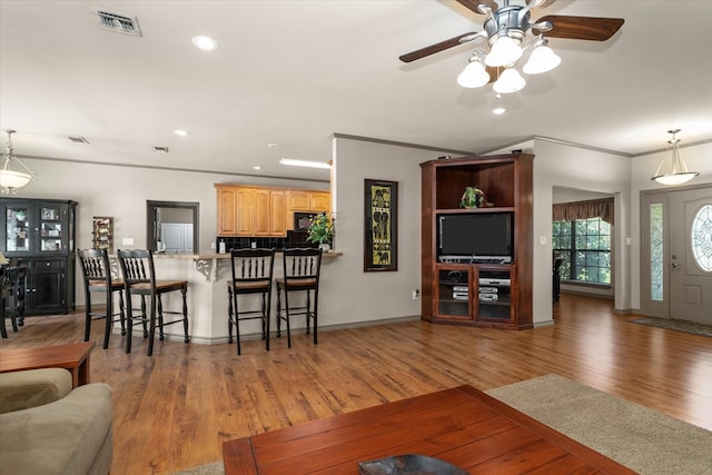 living room featuring dark hardwood / wood-style flooring, ceiling fan, and crown molding