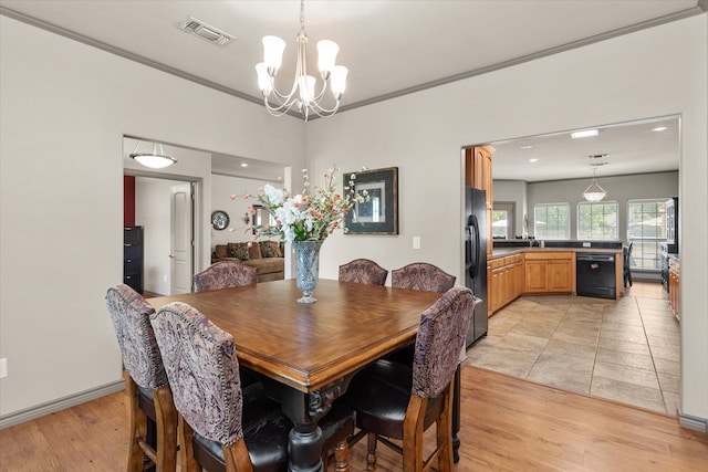 dining space featuring a chandelier, light hardwood / wood-style flooring, ornamental molding, and sink