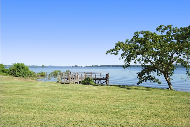 view of dock with a lawn and a water view