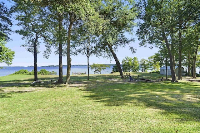 surrounding community with a water view and a yard