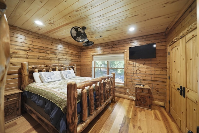 bedroom with wood ceiling, wooden walls, and light hardwood / wood-style floors