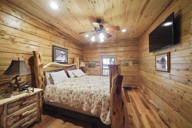 bedroom with ceiling fan, wooden ceiling, wood walls, and hardwood / wood-style flooring