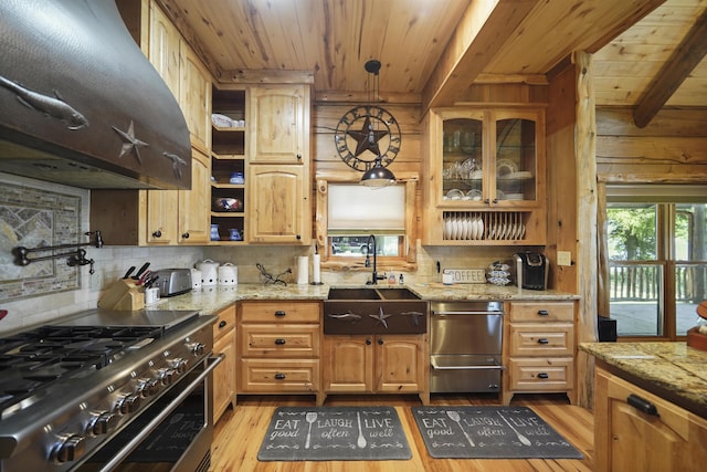 kitchen with high end range, light wood-type flooring, light stone counters, sink, and pendant lighting