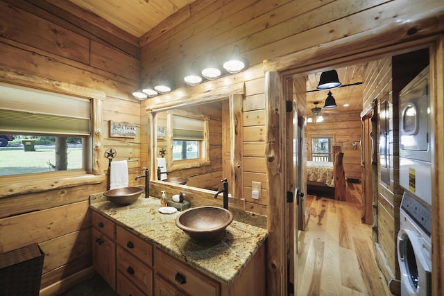 bathroom featuring vanity, wooden ceiling, stacked washer and dryer, wooden walls, and hardwood / wood-style flooring