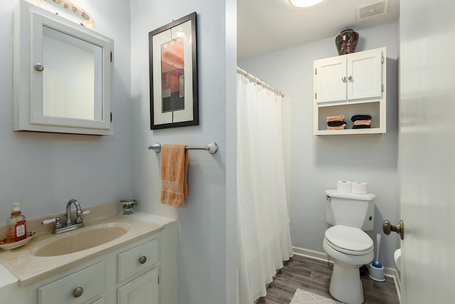 full bathroom with wood finished floors, vanity, curtained shower, toilet, and visible vents