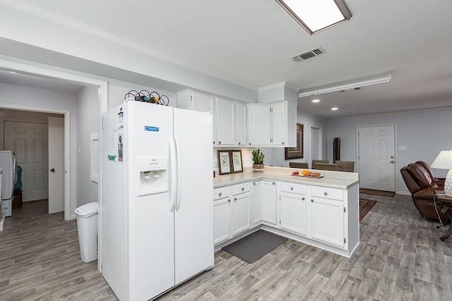 kitchen with light countertops, ornamental molding, a peninsula, white fridge with ice dispenser, and light wood-style flooring
