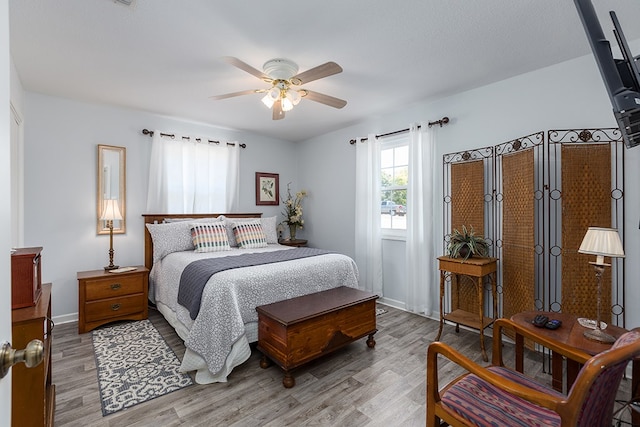 bedroom with light wood-style floors, baseboards, and ceiling fan