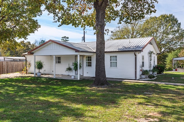 back of property featuring fence, a lawn, and metal roof
