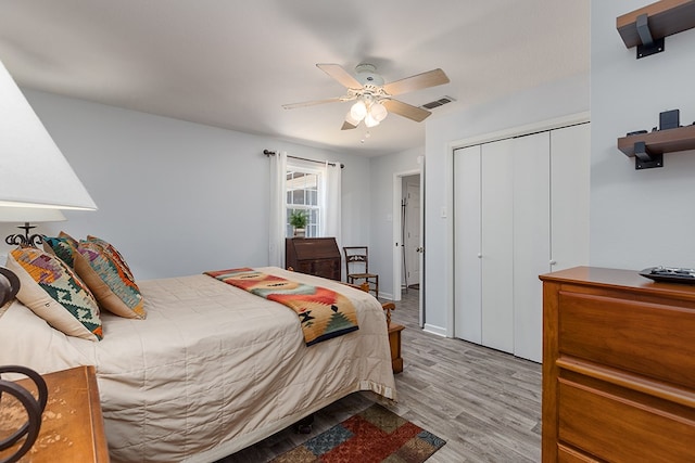 bedroom with wood finished floors, visible vents, a closet, and a ceiling fan