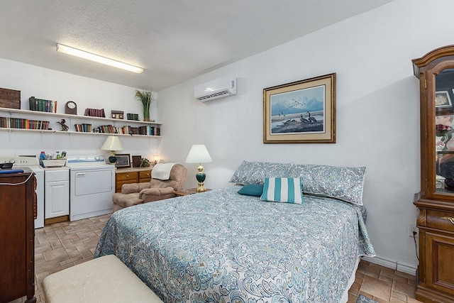 bedroom featuring a wall mounted air conditioner, stone finish flooring, and washer and clothes dryer