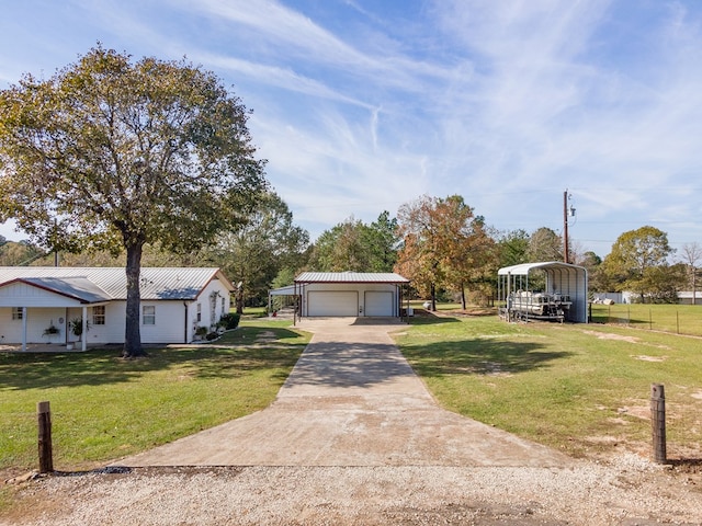 view of front of property featuring metal roof, a front lawn, an outbuilding, a carport, and a garage