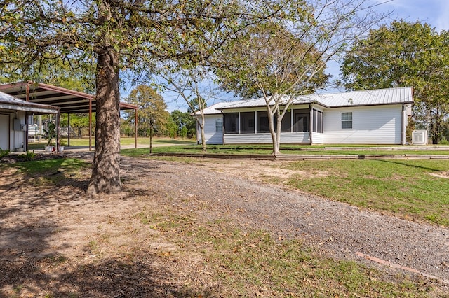 view of front of property featuring a carport, a sunroom, a front yard, and metal roof