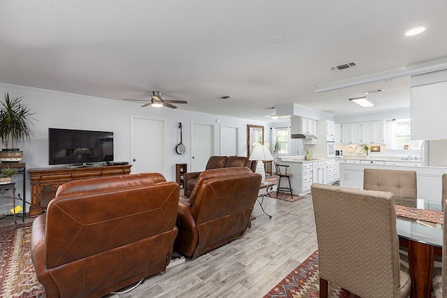 living room with visible vents, recessed lighting, light wood-style floors, a ceiling fan, and crown molding