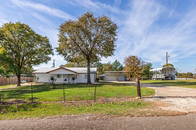 single story home featuring driveway, an outdoor structure, fence, a front yard, and a detached carport