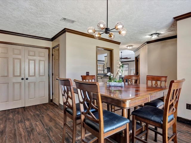 dining space with dark wood-type flooring, visible vents, ornamental molding, and a textured ceiling