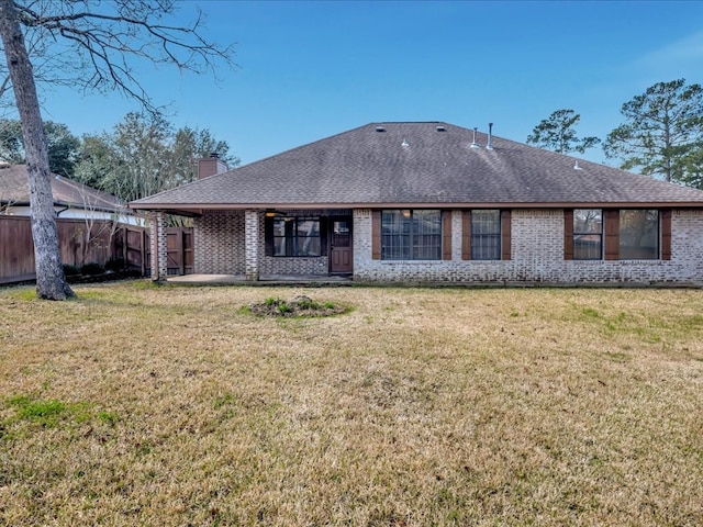 back of house with a yard, brick siding, and fence