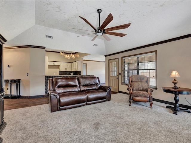 carpeted living room featuring a textured ceiling, lofted ceiling, visible vents, baseboards, and ornamental molding