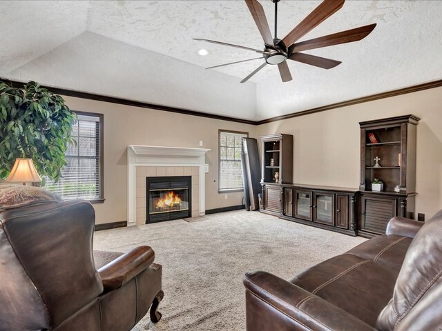 living area with crown molding, a fireplace, carpet flooring, vaulted ceiling, and a textured ceiling