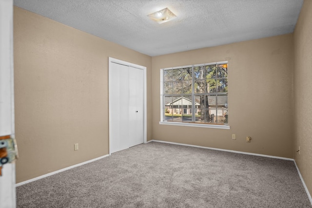 spare room featuring a textured ceiling and carpet