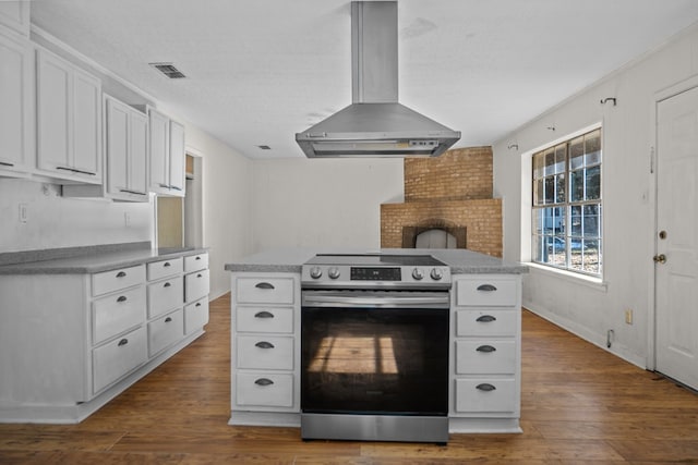 kitchen featuring island range hood, wood-type flooring, stainless steel electric range oven, a kitchen island, and white cabinetry