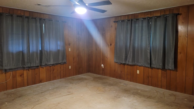 spare room with ceiling fan and wood walls