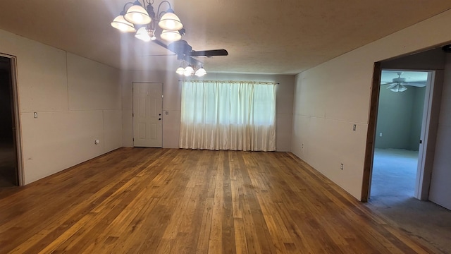 unfurnished room with ceiling fan with notable chandelier and hardwood / wood-style flooring