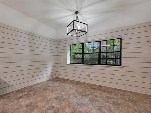 602 April Dr, Lufkin, TX 75904 - empty room featuring wood walls, plenty of natural light, and a chandelier