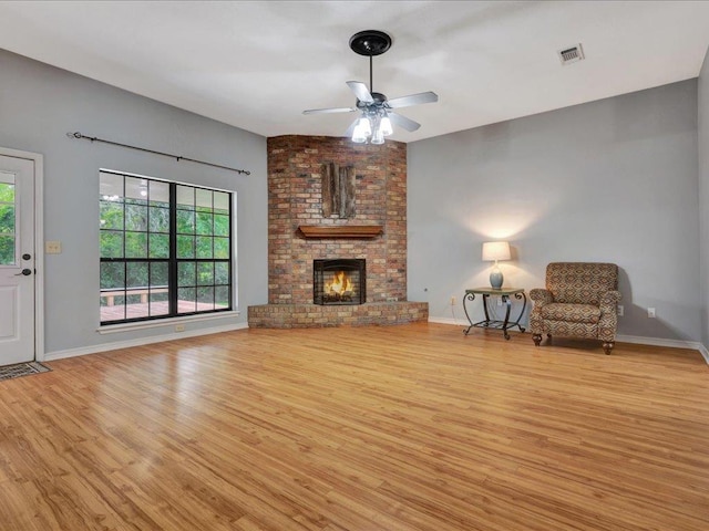 602 April Dr, Lufkin, TX 75904 - unfurnished living room featuring wood finished floors, a ceiling fan, and a brick fireplace