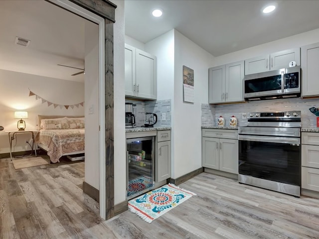 516 Westchester St, Diboll, TX 75941 - kitchen featuring appliances with stainless steel finishes, beverage cooler, light wood finished floors, tasteful backsplash, and recessed lighting