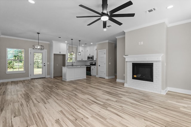 unfurnished living room with crown molding, a fireplace, ceiling fan, and light hardwood / wood-style floors