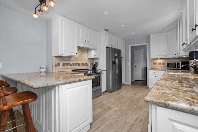 1504 Azalea Dr, Lufkin, TX 75904 - kitchen featuring stainless steel appliances, a peninsula, white cabinets, a sink, and backsplash