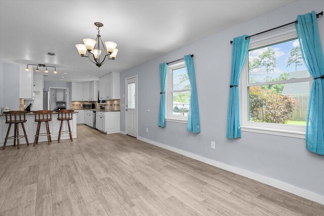 1504 Azalea Dr, Lufkin, TX 75904 - kitchen with a chandelier, white cabinets, light wood-type flooring, baseboards, and stainless steel microwave