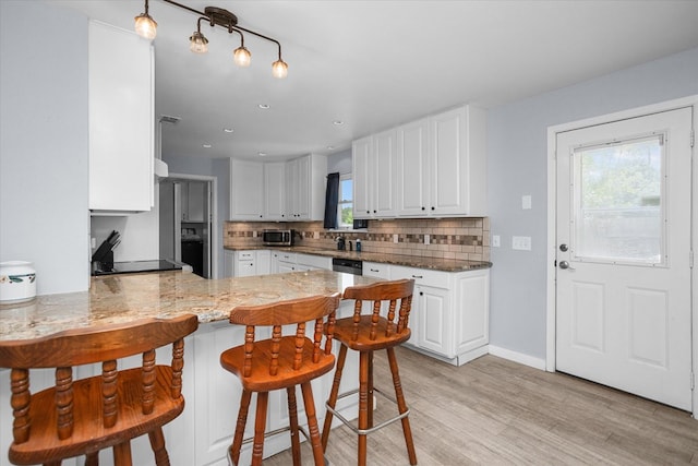 1504 Azalea Dr, Lufkin, TX 75904 - kitchen featuring a peninsula, backsplash, light wood-style flooring, white cabinets, and recessed lighting