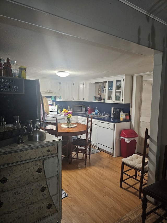 2606 Brentwood Dr, Lufkin, TX 75901 - kitchen featuring stainless steel microwave, dishwasher, white cabinetry, light wood finished floors, and dark countertops