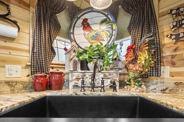 interior details with wood walls, light stone countertops, and sink