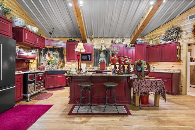 kitchen featuring stainless steel fridge, light wood-type flooring, vaulted ceiling with beams, black microwave, and a center island